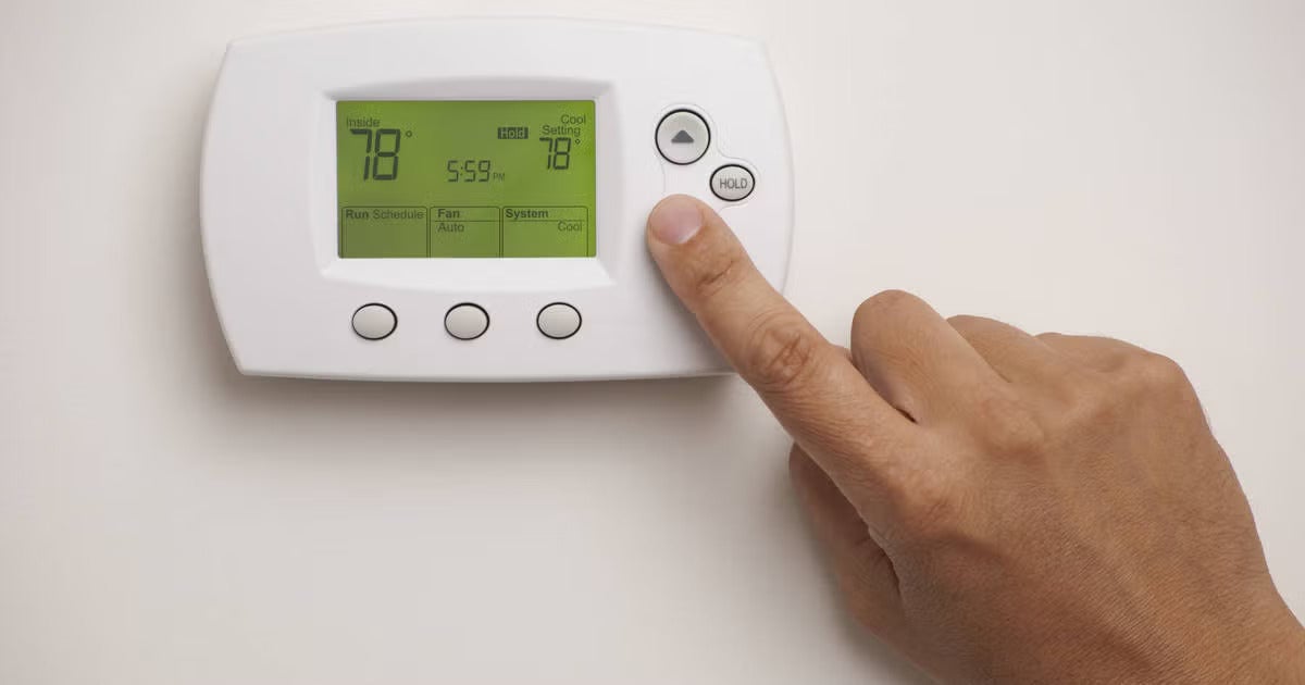 Person adjusting a home thermostat