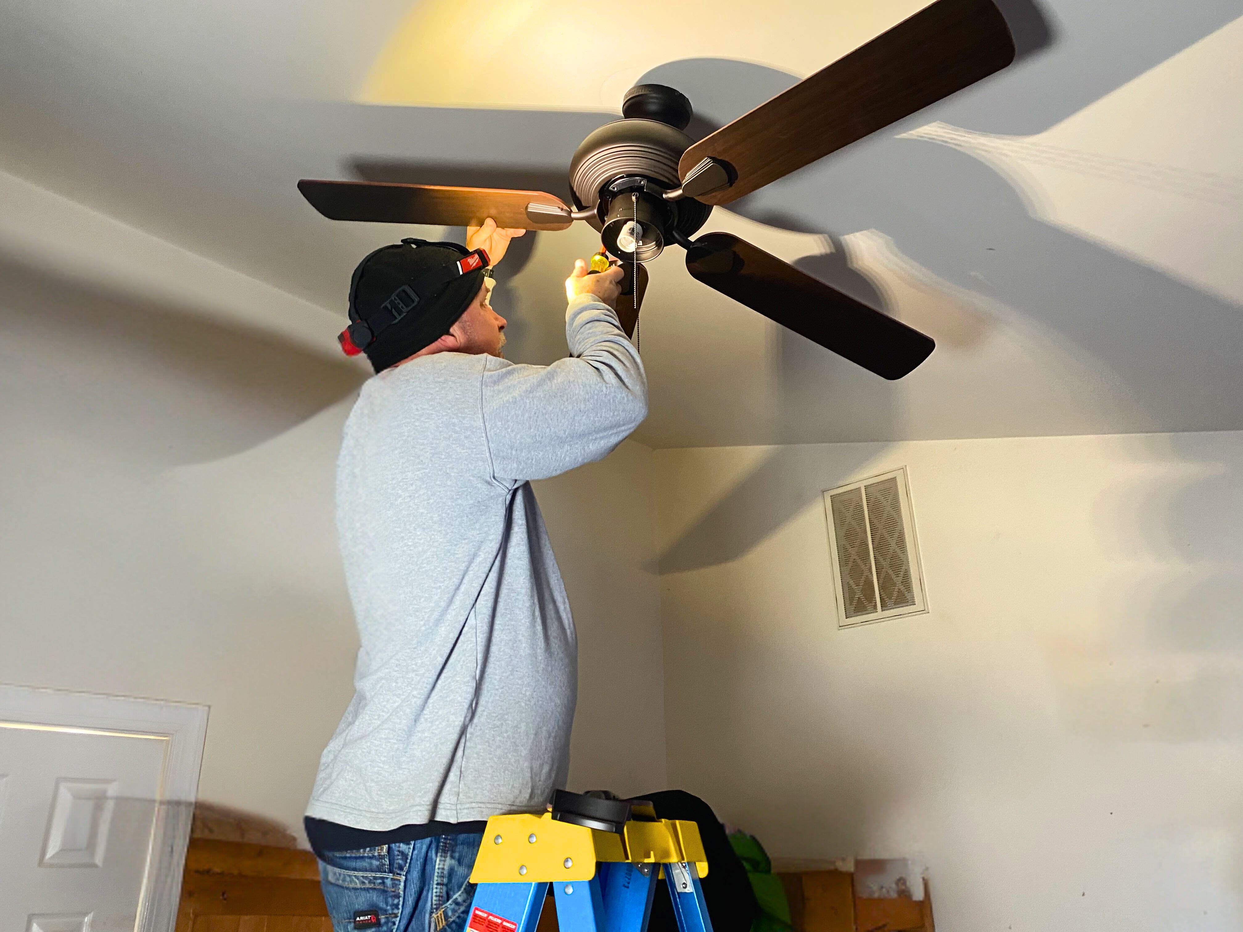 Electrician installing a ceiling fan