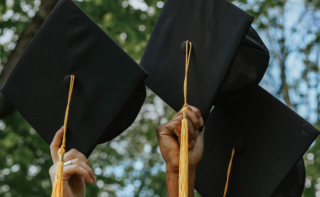 Graduation caps being held up in the air.
